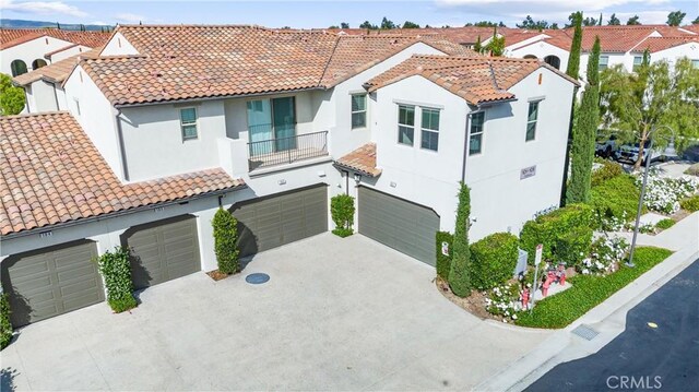 mediterranean / spanish-style home featuring stucco siding, an attached garage, driveway, and a tiled roof