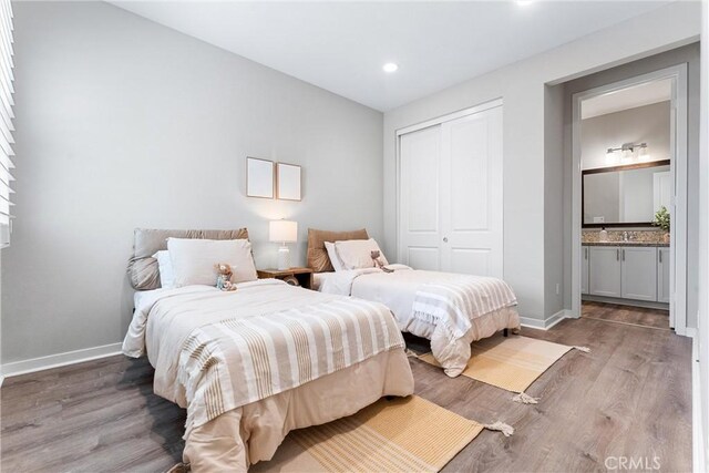 bedroom with a closet, wood finished floors, baseboards, and recessed lighting