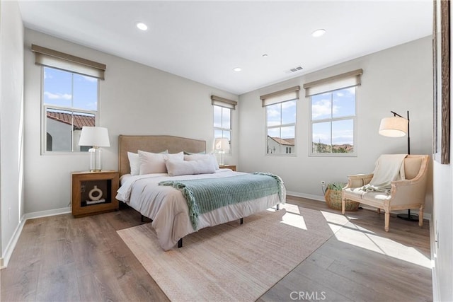 bedroom featuring multiple windows, wood finished floors, baseboards, and recessed lighting