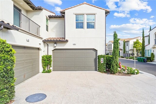 view of front of home with a garage, stucco siding, a tiled roof, a residential view, and concrete driveway