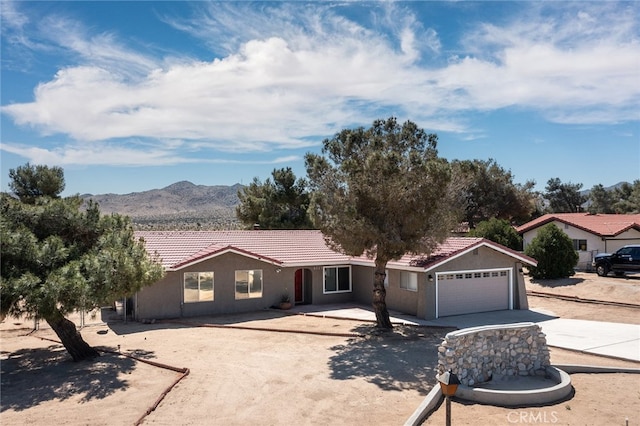 8723 Palomar Ave, Yucca Valley, CA 92284 - ranch-style home featuring a tiled roof, concrete driveway, an attached garage, a mountain view, and stucco siding