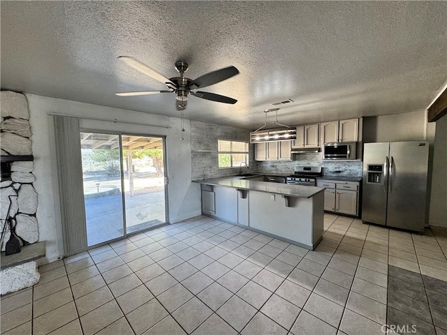 8723 Palomar Ave, Yucca Valley, CA 92284 - kitchen with stainless steel appliances, a peninsula, light tile patterned floors, a ceiling fan, and a textured ceiling