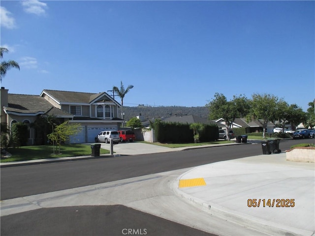 view of asphalt road featuring curbs, a residential view, and sidewalks