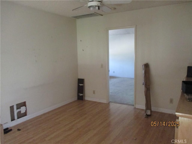 empty room with a ceiling fan, wood finished floors, and baseboards
