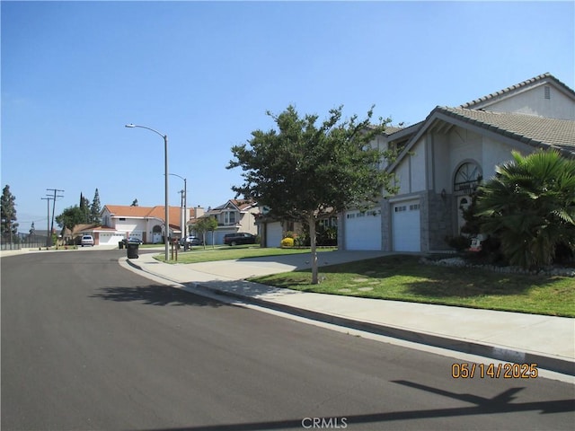 view of asphalt road featuring street lights, sidewalks, a residential view, and curbs
