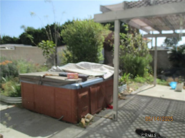 view of patio / terrace with a hot tub and fence