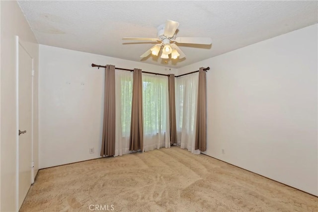 empty room featuring light colored carpet and a ceiling fan