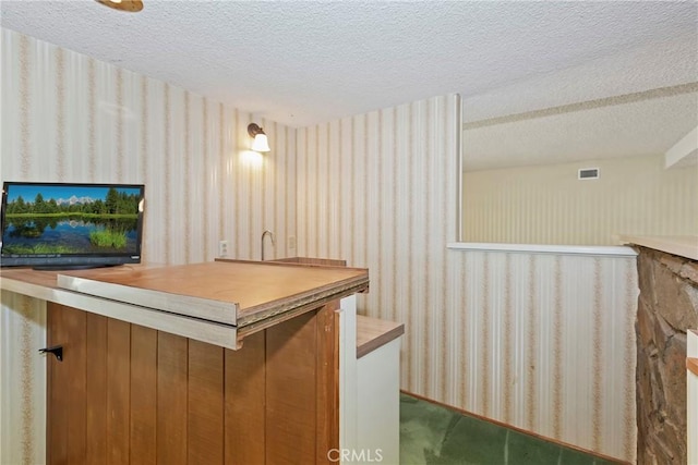 bar area featuring wallpapered walls, a textured ceiling, and carpet