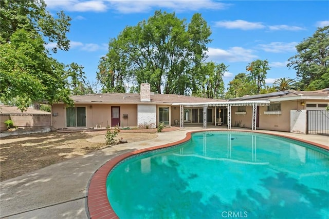 outdoor pool featuring fence and a patio