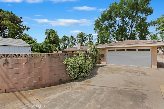 view of property exterior with fence, stucco siding, driveway, and an attached garage