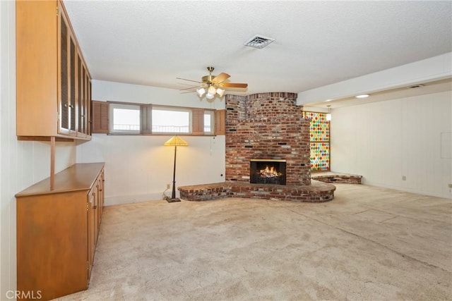 unfurnished living room featuring ceiling fan, plenty of natural light, light colored carpet, and a textured ceiling