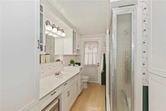 full bathroom with toilet, vanity, a shower stall, and wood finished floors
