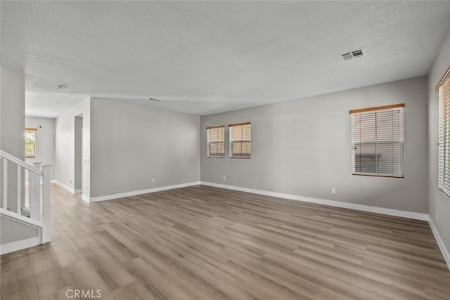 2455 Delicious Ln, Palmdale, CA 93551 - empty room featuring a textured ceiling, wood finished floors, baseboards, and stairway