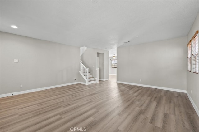 2455 Delicious Ln, Palmdale, CA 93551 - unfurnished living room featuring light wood-style flooring, stairway, baseboards, and recessed lighting