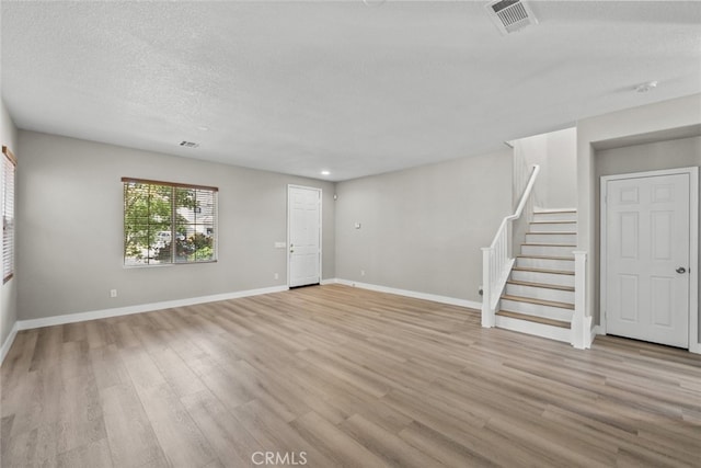 2455 Delicious Ln, Palmdale, CA 93551 - unfurnished living room with stairs, light wood-style flooring, baseboards, recessed lighting, and a textured ceiling