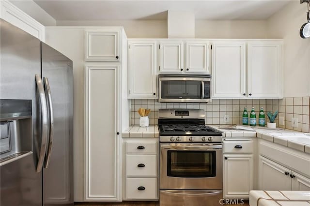 1304 12th St Unit B, Manhattan Beach, CA 90266 - kitchen featuring appliances with stainless steel finishes, tile countertops, white cabinets, and decorative backsplash
