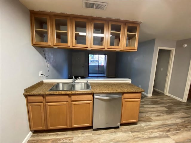 1114 Nord Ave Unit 11, Chico, CA 95926 - kitchen with stainless steel dishwasher, a sink, brown cabinetry, glass insert cabinets, and baseboards