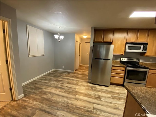 1114 Nord Ave Unit 11, Chico, CA 95926 - kitchen with stainless steel appliances, a chandelier, baseboards, light wood-type flooring, and decorative light fixtures