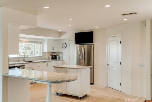 425 Calle Cielo, Nipomo, CA 93444 - kitchen featuring a center island, freestanding refrigerator, decorative backsplash, white cabinetry, and light stone counters