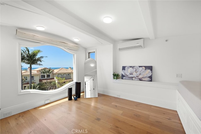 530 Kings Rd, Newport Beach, CA 92663 - unfurnished living room featuring a wall unit AC, beamed ceiling, wood finished floors, and baseboards