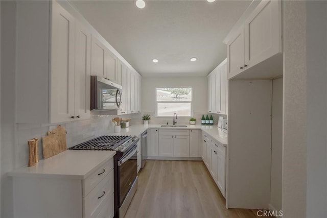 16739 Mission St, Hesperia, CA 92345 - kitchen featuring appliances with stainless steel finishes, decorative backsplash, white cabinets, light wood-style flooring, and recessed lighting