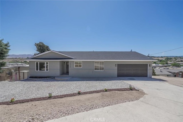 16739 Mission St, Hesperia, CA 92345 - ranch-style home featuring concrete driveway, a garage, stucco siding, and roof with shingles