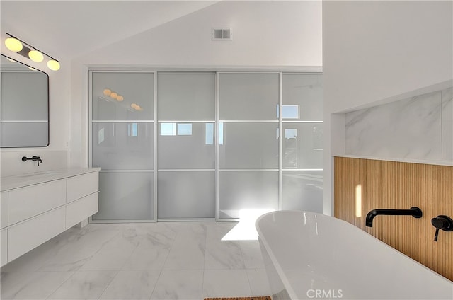 27 Burriana, San Clemente, CA 92672 - full bathroom featuring marble look tiles, vaulted ceiling, a freestanding tub, vanity, and a shower