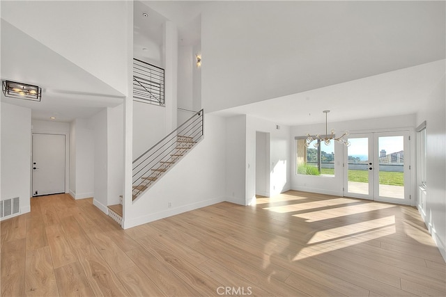 27 Burriana, San Clemente, CA 92672 - unfurnished living room with a towering ceiling, stairs, light wood-type flooring, and baseboards