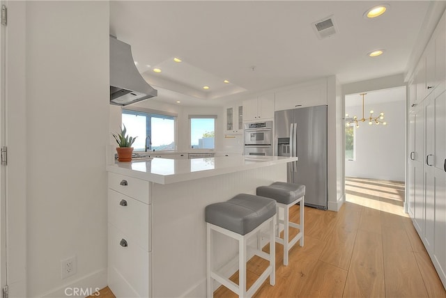 27 Burriana, San Clemente, CA 92672 - kitchen with appliances with stainless steel finishes, ventilation hood, white cabinetry, recessed lighting, and light wood finished floors