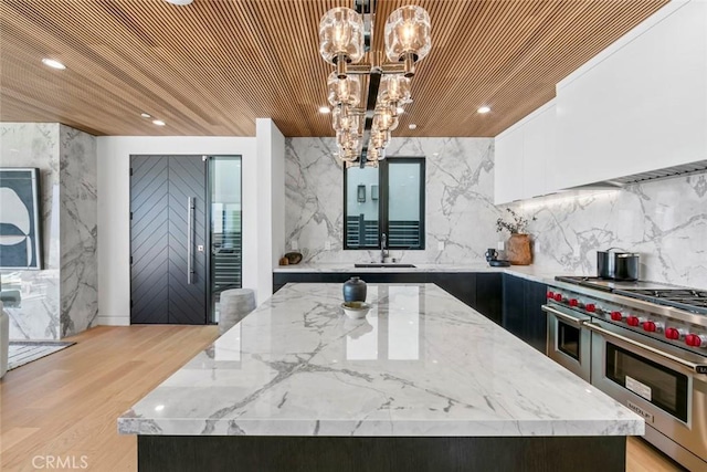 5007 Seashore Dr, Newport Beach, CA 92663 - kitchen with range with two ovens, a chandelier, a center island, a sink, and light stone counters