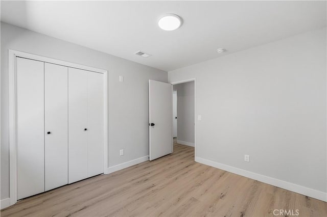 unfurnished bedroom with wood finished floors, baseboards, and a closet
