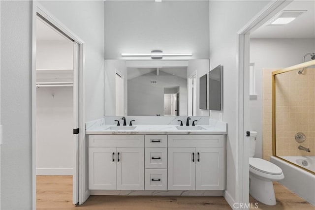 full bath featuring wood finished floors, toilet, double vanity, and  shower combination