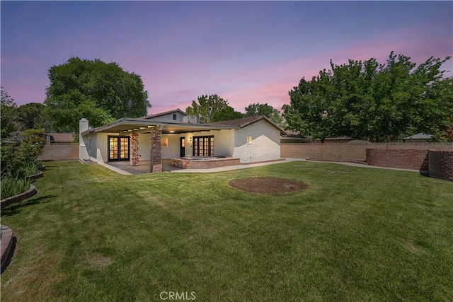 rear view of house with french doors, stucco siding, and a patio