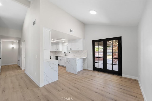kitchen featuring white cabinetry, high vaulted ceiling, light wood-type flooring, a sink, and decorative backsplash