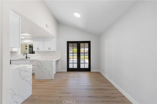 doorway to outside with vaulted ceiling, french doors, light wood-style floors, baseboards, and a sink