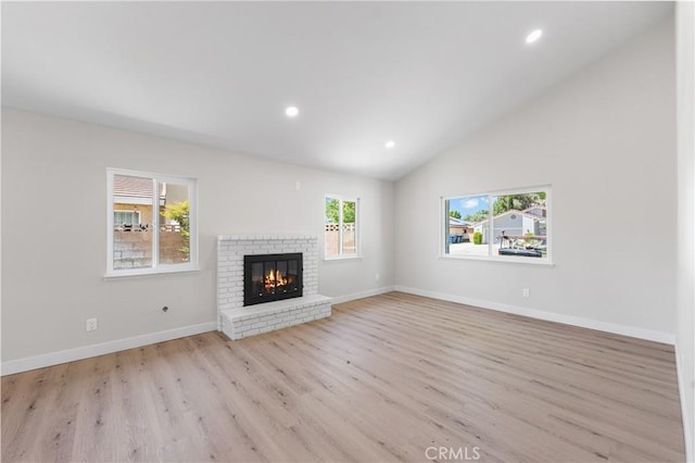 unfurnished living room with light wood-type flooring, a fireplace, recessed lighting, vaulted ceiling, and baseboards