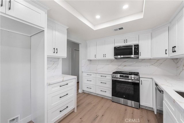 kitchen with appliances with stainless steel finishes, white cabinets, light stone counters, tasteful backsplash, and recessed lighting