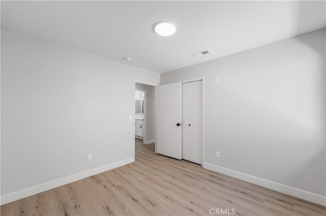unfurnished bedroom with baseboards, wood finished floors, and a closet