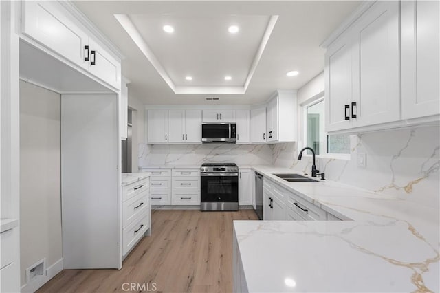 kitchen with appliances with stainless steel finishes, a sink, decorative backsplash, recessed lighting, and light wood-style flooring