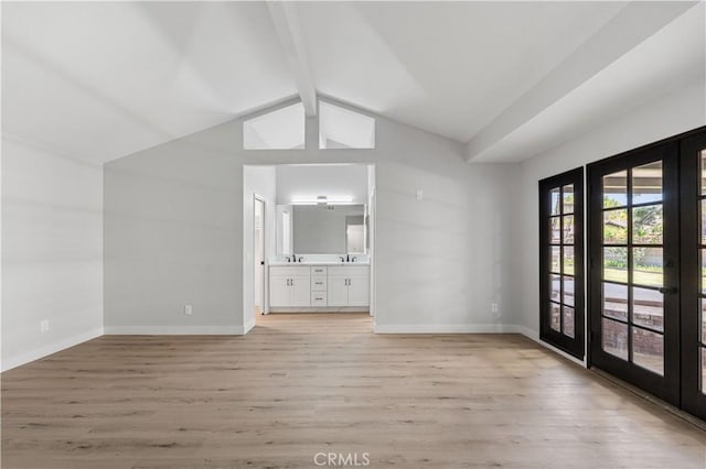 unfurnished living room featuring french doors, light wood finished floors, and baseboards