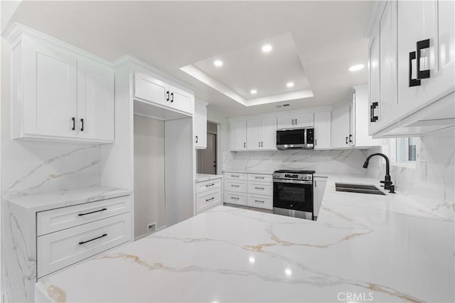 kitchen with appliances with stainless steel finishes, a sink, recessed lighting, backsplash, and light stone countertops