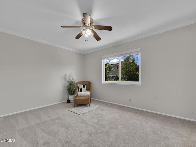 sitting room with ceiling fan, carpet floors, ornamental molding, and baseboards