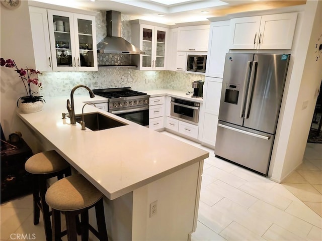 6 Whittier Ct, Rancho Mirage, CA 92270 - kitchen with stainless steel appliances, wall chimney range hood, a sink, a peninsula, and decorative backsplash