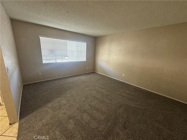 carpeted empty room featuring a textured ceiling and baseboards
