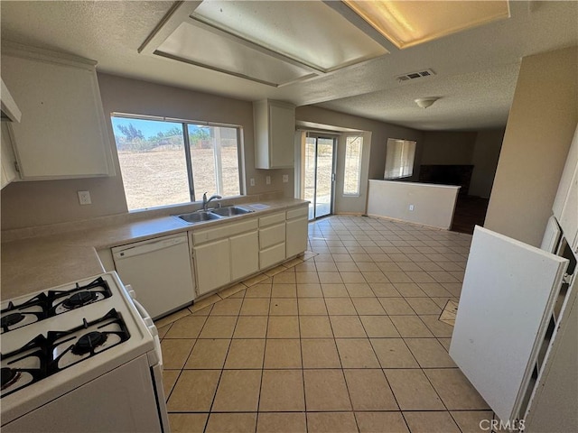 kitchen with white appliances, a sink, light countertops, white cabinets, and a textured ceiling