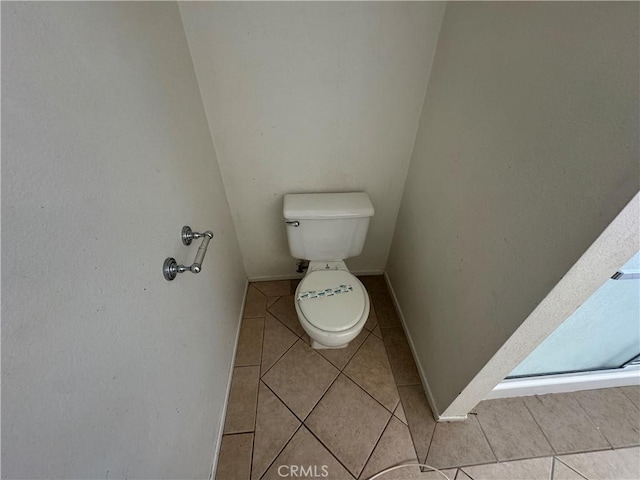 bathroom with tile patterned floors, toilet, and baseboards