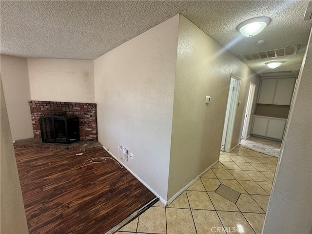 hall with a textured ceiling, light tile patterned flooring, and baseboards