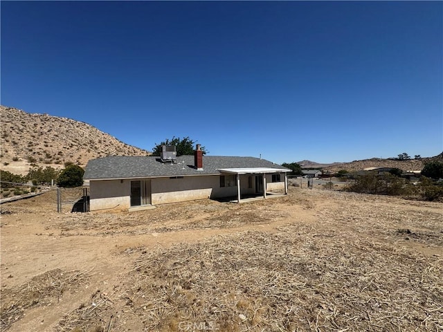 back of house with a mountain view, a chimney, and fence