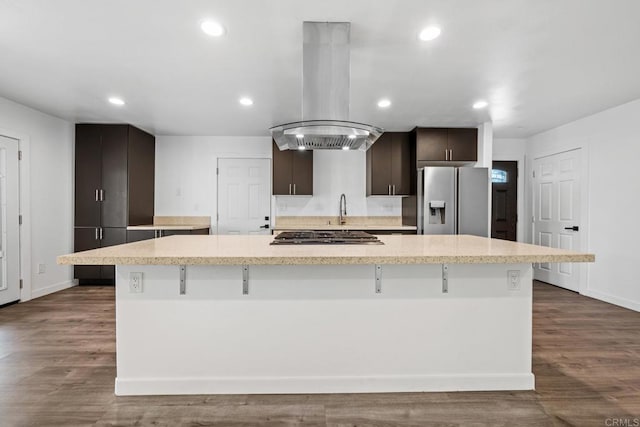 4585 Mount Henry Pl, San Diego, CA 92117 - kitchen with appliances with stainless steel finishes, island exhaust hood, light countertops, dark brown cabinetry, and a kitchen bar