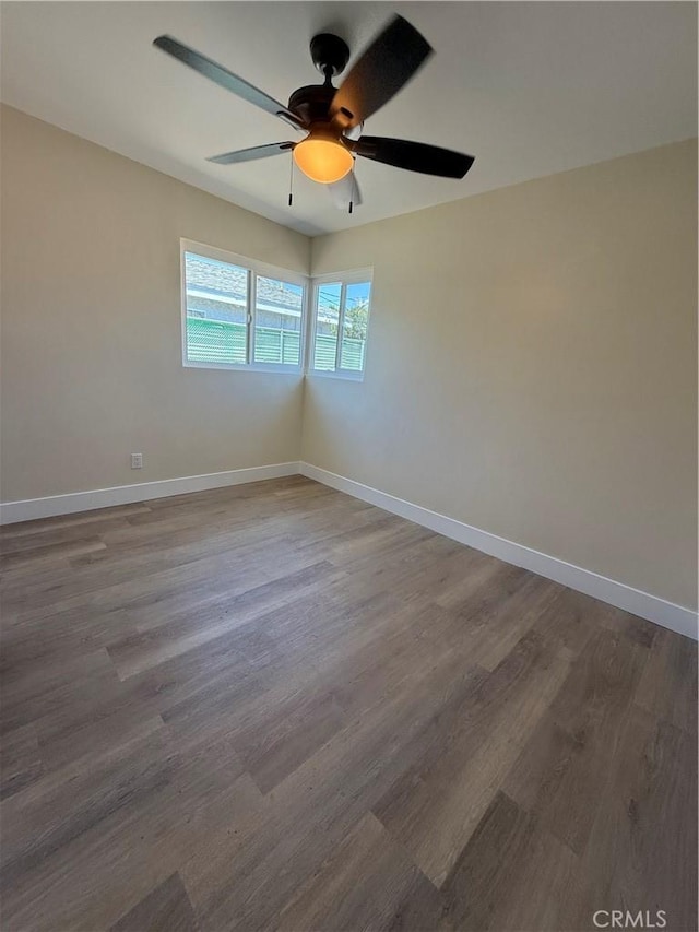 spare room featuring ceiling fan, wood finished floors, and baseboards